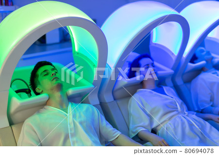 Male and female relaxing on massaging chairs Male and female relaxing on massaging chairs 80694078
