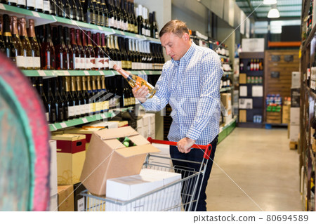Male customer choosing wine in supermarket Male customer choosing wine in supermarket 80694589