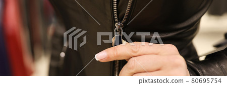Woman zips up black leather jacket closeup Woman zips up black leather jacket closeup 80695754