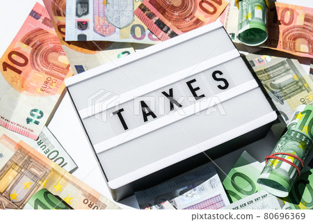 Lightbox board with word TAXES in black letters around Euro banknotes. Tax payment and filing concept. Money, Business, finance, investment, saving and corruption 80696369