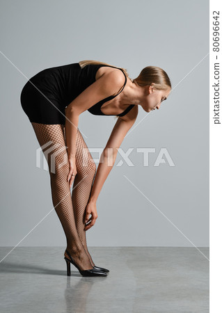 Young woman lean forward and touching her leg Young woman lean forward and touching her leg 80696642