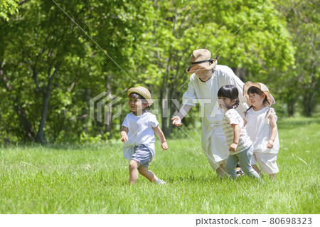 Nursery teachers and children playing in the field 80698323