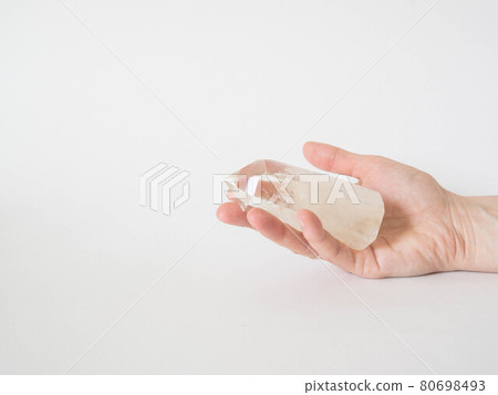 Beautiful Clear Quartz tower in woman hand. Quartz crystal, healing crystal being held in hand. Vibrant meditation. Copy space. Front view 80698493