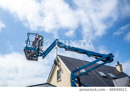 Worker on a aerial access platform, cherry picker, cleaning house 80699021