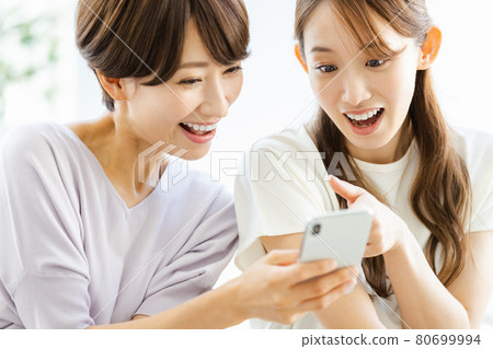 兩個女人一邊看智能手機一邊聊天 80699994