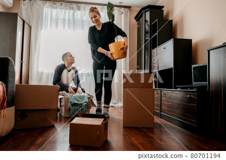 Moving day, Move Into New Home. Young happy couple, newlyweds family having fun in room with houseplant and carton boxes prepared for moving in or moving out of home Moving day, Move Into New Home. Young happy couple, newlyweds family having fun in room with houseplant and carton boxes prepared for moving in or moving out of home 80701194