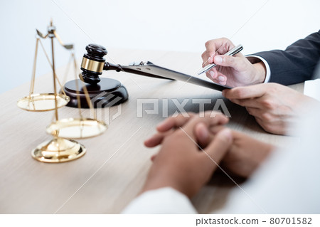 A male lawyer or a judge counseling clients about judicial justice and prosecution with scales, judges gavel, legal documents legal services concept 80701582