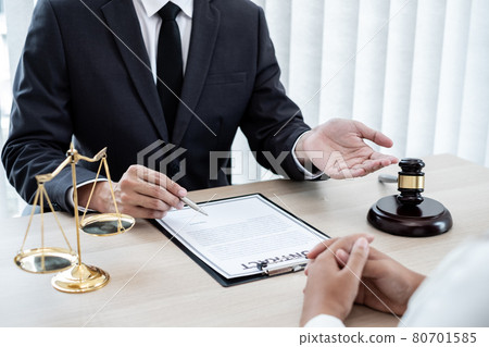 A male lawyer or a judge counseling clients about judicial justice and prosecution with scales, judges gavel, legal documents legal services concept 80701585