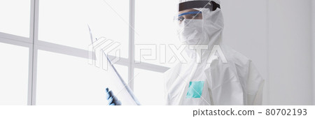 Doctor in protective suit and mask is holding an X-ray Doctor in protective suit and mask is holding an X-ray 80702193