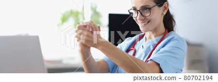 Smiling female doctor looks into laptop monitor and gives advice to patient Smiling female doctor looks into laptop monitor and gives advice to patient 80702194