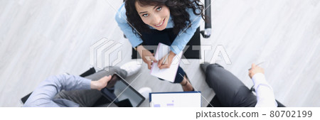 Business partners are sitting at table smiling and looking up Business partners are sitting at table smiling and looking up 80702199