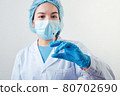 Closeup vial of covid-19 vaccine in hand of professional scientist or doctor in laboratory for treatment with mask gloves and lab coat on white background. Health business and industry concept. 80702690