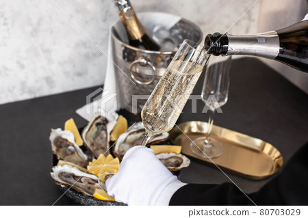 Hand of waiter with white glove pouring champagne Hand of waiter with white glove pouring champagne 80703029