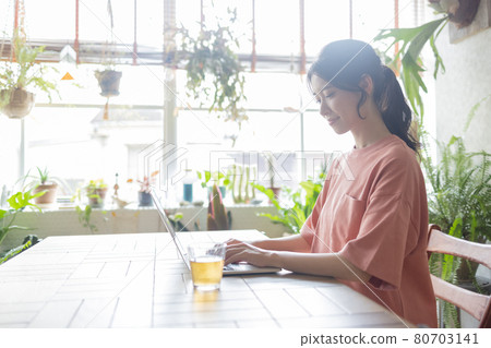 A young woman who plays a personal computer in a room 80703141