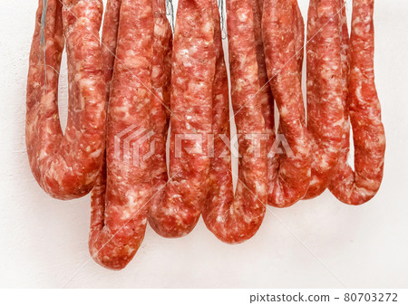 Drying pile of sausages from raw minced meat on a white wall background at home, close up Drying pile of sausages from raw minced meat on a white wall background at home, close up 80703272