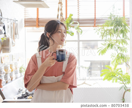 A woman drinking coffee in the kitchen A woman drinking coffee in the kitchen 80703438