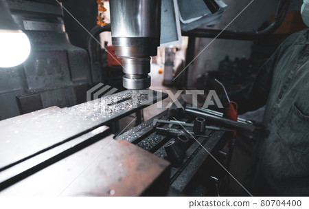 Milling machine working near worker with a protective mask. Tool for cut metal workpiece. Vertical milling machine with cemented carbide milling cutter. Steel manufacturing industry. Milling process. Milling machine working near worker with a protective mask. Tool for cut metal workpiece. Vertical milling machine with cemented carbide milling cutter. Steel manufacturing industry. Milling process. 80704400