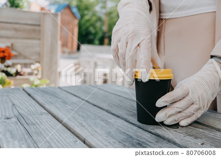 Food and drink businesses during coronavirus pandemic. Coffee to go takeaway cup in female hands in gloves. Restaurants, pubs, bars, nightclubs and takeaway services working safely during coronavirus 80706008