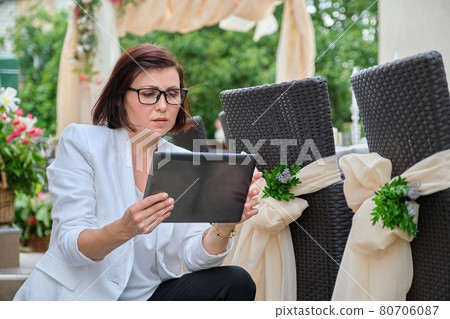 Woman professional decorator with digital tablet working outdoors decorating ceremony 80706087