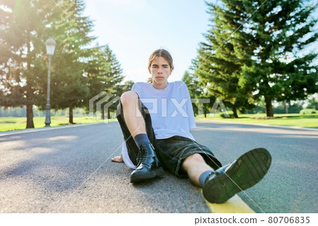 Fashion portrait of hipster teenager guy sitting on the road. 80706835