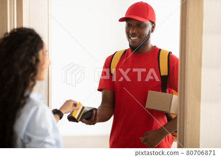 Black man holding POS terminal client lady paying with bankcard Black man holding POS terminal client lady paying with bankcard 80706871