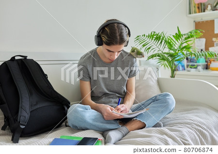 Male teenager with pet parrot, guy student sitting in headphones at home Male teenager with pet parrot, guy student sitting in headphones at home 80706874