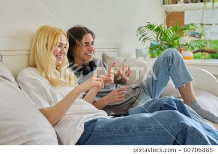 Happy laughing hipster teenagers male and female having fun using smartphone together 80706888