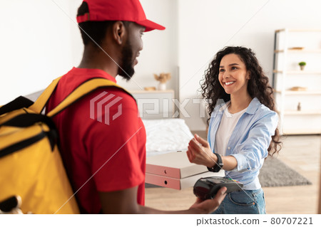 Black delivery man holding POS machine, customer paying with watch Black delivery man holding POS machine, customer paying with watch 80707221