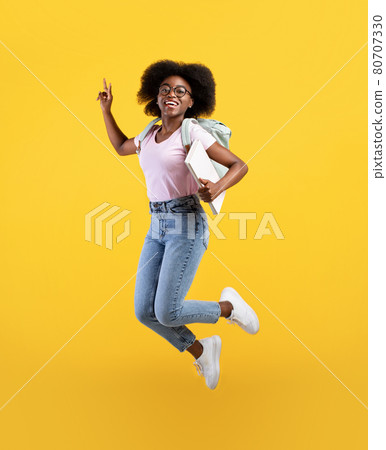 Enjoying student life. Full length portrait of african american lady jumping, wearing backpack and holding notepads 80707330