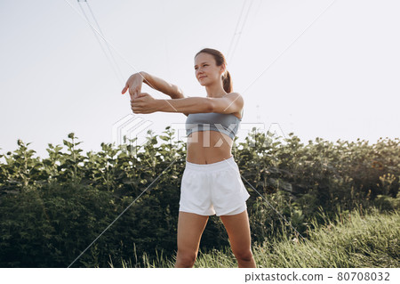 Young slim sportive caucasian woman working out, doing fitness, yoga outdoors in the sunflower field Young slim sportive caucasian woman working out, doing fitness, yoga outdoors in the sunflower field 80708032
