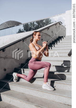 Side view. Young slim sportive caucasian woman working out, doing fitness, yoga on the stairs on city street. Side view. Young slim sportive caucasian woman working out, doing fitness, yoga on the stairs on city street. 80708101