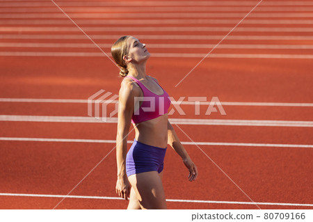 One Caucasian woman, female athlete, runner training at public stadium, sport court or palyground outdoors. Summer sport games. 80709166