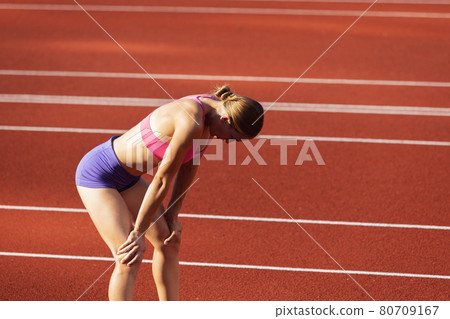 One Caucasian woman, female athlete, runner training at public stadium, sport court or palyground outdoors. Summer sport games. One Caucasian woman, female athlete, runner training at public stadium, sport court or palyground outdoors. Summer sport games. 80709167