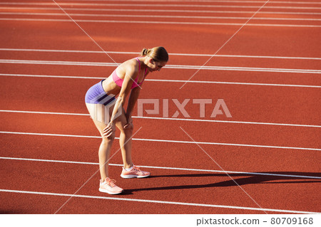 One Caucasian woman, female athlete, runner training at public stadium, sport court or palyground outdoors. Summer sport games. One Caucasian woman, female athlete, runner training at public stadium, sport court or palyground outdoors. Summer sport games. 80709168