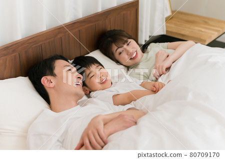 A family of three sleeping in the shape of a river on the bed in the bedroom 80709170