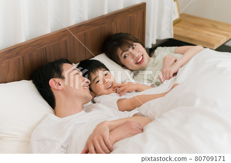 一個三口之家睡在臥室床上的河流形狀 一個三口之家睡在臥室床上的河流形狀 80709171