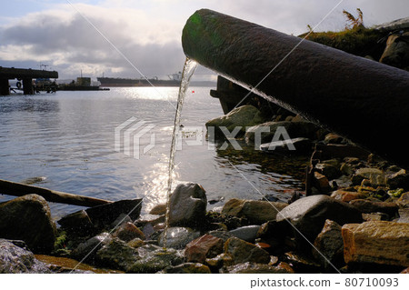 Water pours from a rusty pipe to the coastal part. Environmental protection, pollution of the world's oceans. The Barents Sea. Water pours from a rusty pipe to the coastal part. Environmental protection, pollution of the world's oceans. The Barents Sea. 80710093