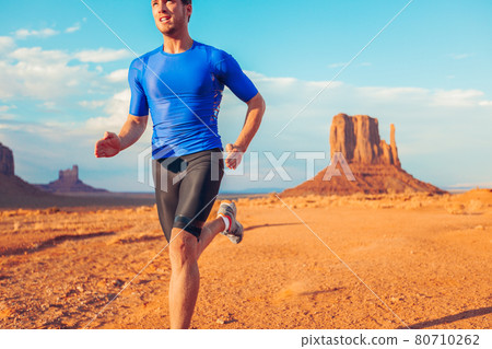Ultra running competition trail runner man athlete sprinting across desert landscape in Monument Valley, Arizona, USA. Outdoor sport high intensity endurance training 80710262
