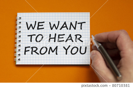 Support symbol. White note with words 'we want to here from you'. Businessman hand with pen. Beautiful orange background, copy space. Business and support concept. Support symbol. White note with words 'we want to here from you'. Businessman hand with pen. Beautiful orange background, copy space. Business and support concept. 80710381