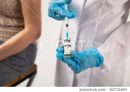Doctor prepares a syringe with coronavirus vaccine for a patient. Doctor prepares a syringe with coronavirus vaccine for a patient. 80710484