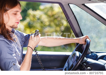 Young man driving car using cb radio Young man driving car using cb radio 80710791