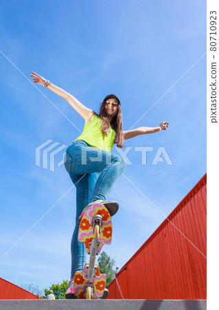 Teen girl skater riding skateboard on street. 80710923