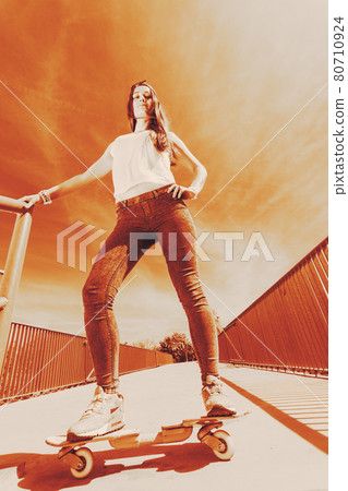 Teenage girl skater riding skateboard on street. 80710924