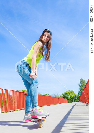 Teen girl skater riding skateboard on street. 80710925