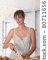 Young woman cutting fruits in the kitchen while looking away 80711656