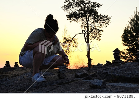 Woman make little stone pyramids in Karelija 80711893