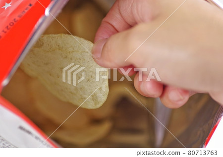 A woman eating potato chips A woman eating potato chips 80713763