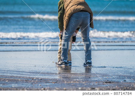 [Grandpa working hard so that his grandchildren do not get wet at the beach] 80714784