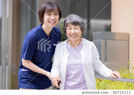 Nursing image: Senior woman walking with a cane and a caregiver Photographing cooperation: Japanese language school attached to Chuo Institute of Technology 80715111