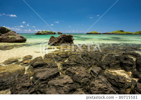 Stunning coastal rocks formation, emerald green sea, blue sky, green islets in the background, blue sky. Iriomote Island. 80715581